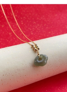 Vue macro d'un pendentif verrou Ruyi en argent S925 et jade Hetian sur chaîne dorée
