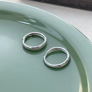 Sparkling S925 sterling silver frosted couple rings on a sage green ceramic plate