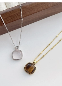 Detail of square rose quartz and tiger eye pendants on bead chains in silver and gold