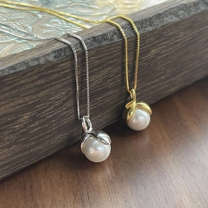 Elegant S925 sterling silver pearl necklace in gold and silver finish hanging on wood