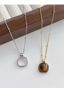 Detailed view of square rose quartz and tiger eye pendants on delicate bead chains