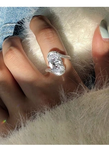 Gros plan sur la bague en zircon ovale avec anneau pavé en S sur un fond en peluche douce
