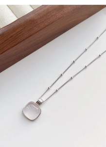 Detail of square cabochon rose quartz pendant on a fine silver bead necklace chain