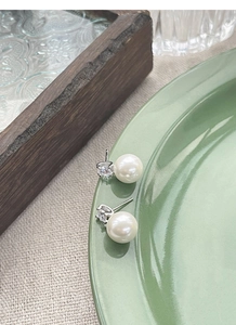 Detailed view of elegant S925 silver pearl stud earrings with sparkling zircons on a tray