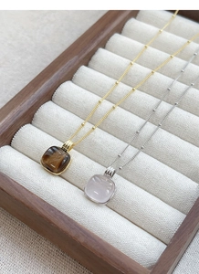 Detail of square tiger eye and pink quartz pendants on beaded sterling silver chains