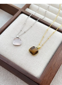Macro detail of square tiger eye and rose quartz pendants on fine beaded link chains