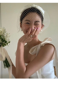 Gros plan d'accessoires de mariée avec bague en perle et voile à nœud en satin blanc