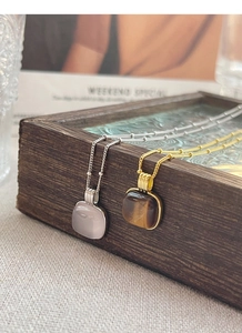 Detail of square rose quartz and tiger eye stone pendants with vintage ribbed metal settings