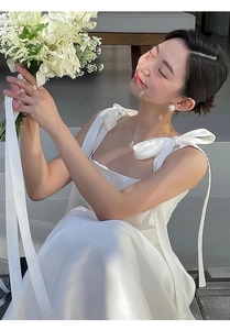 Mariée élégante en robe blanche à nœuds réglables portant des bagues en perles de luxe