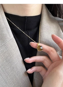 Detail of square tiger eye stone pendant on golden bead chain with vintage style