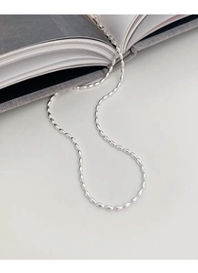 Detailed close-up of S925 silver necklace with minimalist oval link chain on book background