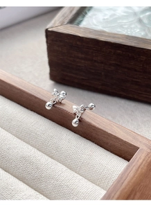 Detailed view of S925 sterling silver bow stud earrings on a dark wood jewelry box