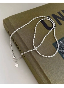 Detail of silver S925 rice bead necklace with lobster clasp and heart pendant on book