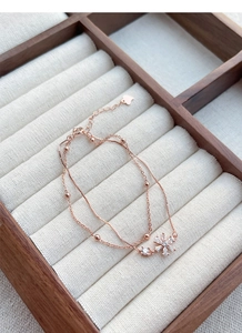 Detail of rose gold double-layer bracelet with cherry blossom zircon and heart tag