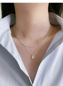 Close-up of minimalist layered S925 silver necklaces with round bead and pearl pendant