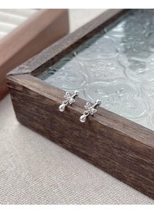 Detailed close-up of S925 sterling silver bow knot ball stud earrings on a vintage tray