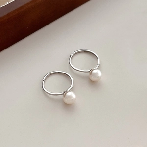Élégantes créoles en argent S925 avec perles blanches rondes sur fond minimaliste chic