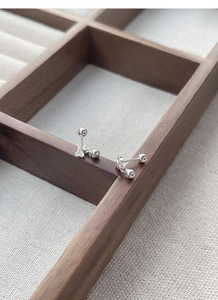 Detailed close-up of S925 sterling silver bow earrings with screw ball back on wood