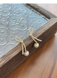 Detail of vintage gold bow earrings with sparkling rhinestones and elegant pearls