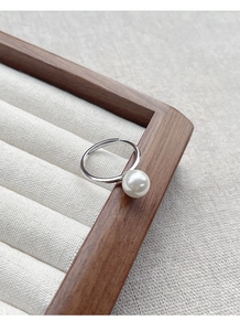 Gros plan d'une bague en argent S925 avec une grande perle blanche sur une boîte en bois