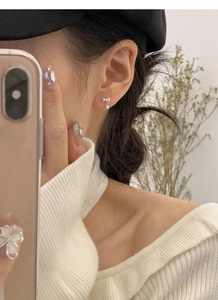 Close-up of S925 sterling silver bow stud earrings with beads worn by a model
