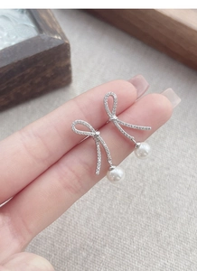 Detailed macro view of S925 silver bowknot earrings with pavé stones and pearls