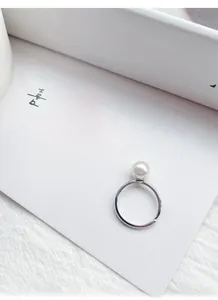 Détail macro d'une bague élégante en argent S925 avec perle blanche et design ouvert