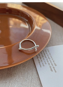 Minimalist S925 sterling silver irregular wave ring on a brown ceramic plate
