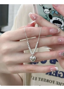 Macro shot of S925 silver heart necklace held in hand showing delicate spiral beads