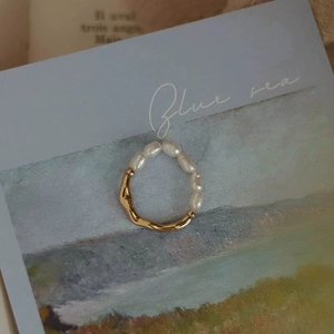 Detailed macro view of gold-tone ripple band ring with five baroque freshwater pearls