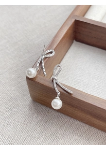 Close-up of S925 silver bow earrings with zircon stones and hanging white pearls