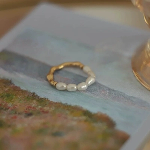 Artistic detail of irregular freshwater pearls and wavy golden ring on oil painting card