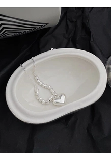 Macro detail of S925 sterling silver heart pendant necklace with spiral beads on a tray
