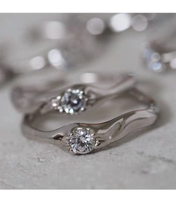 Macro shot of S925 silver couple rings featuring irregular wave texture and center zircon
