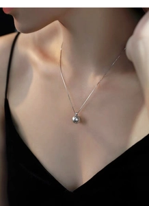 Detail shot of a minimalist S925 sterling silver pearl pendant on a delicate chain necklace