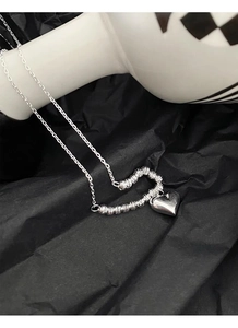 Macro view of textured hollow heart and polished solid heart charm on S925 silver chain