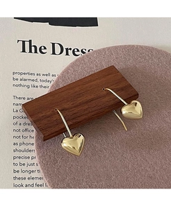 Macro di orecchini a cuore dorati su supporto in legno con decorazione morbida