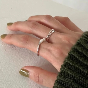 Detail of silver S925 rings with freshwater pearls on hand with green sweater