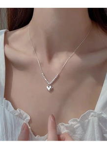 Detailed view of an S925 sterling silver heart necklace with beads on a female model