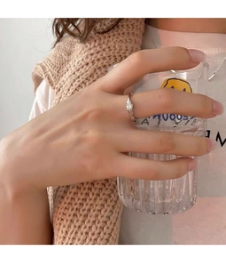 Irregular silver ring with a small diamond shown on hand holding a glass cup