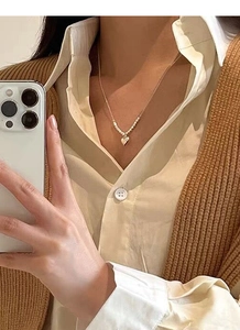 Close-up of a minimalist S925 sterling silver heart necklace with gold beaded chain detail