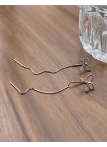Detailed view of S925 silver bow tassel earrings with micro-inlaid zircon on wood surface