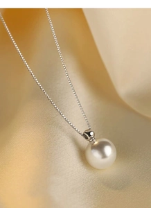 Detailed view of a round white pearl pendant on a fine S925 silver chain over silk