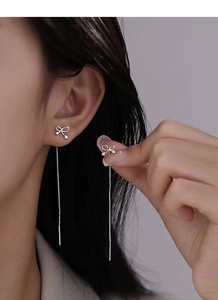 Close-up of S925 sterling silver bow tassel earrings with sparkling zircon accents on model