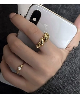 Detail of stacked gold croissant ring and slim zircon band on model wearing knitwear