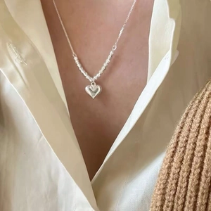Elegant S925 sterling silver heart necklace worn by a model with a soft knitted cardigan