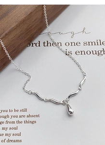 Detailed shot of S925 sterling silver waterdrop pendant necklace on a wooden display