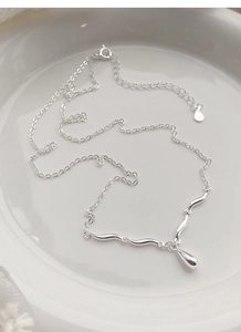 Macro view of minimalist S925 sterling silver waterdrop pendant on fine chain necklace