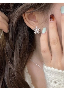 Detailed close-up of a silver sunflower stud earring worn by a model with beaded edges