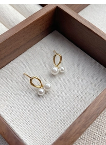 Détail de boucles d'oreilles perles dorées élégantes sur un plateau de bijoux en bois